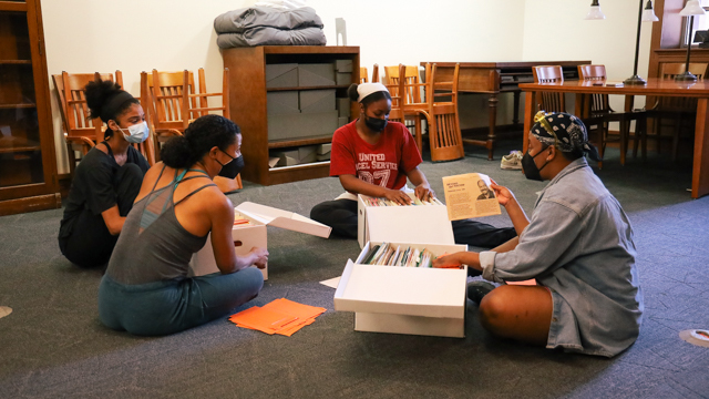 Stiggers, Mozie, Bauman, and Hailes discuss materials from the Dr. William R. Jones Archive in<br>the Special Collections and Archives reading room.